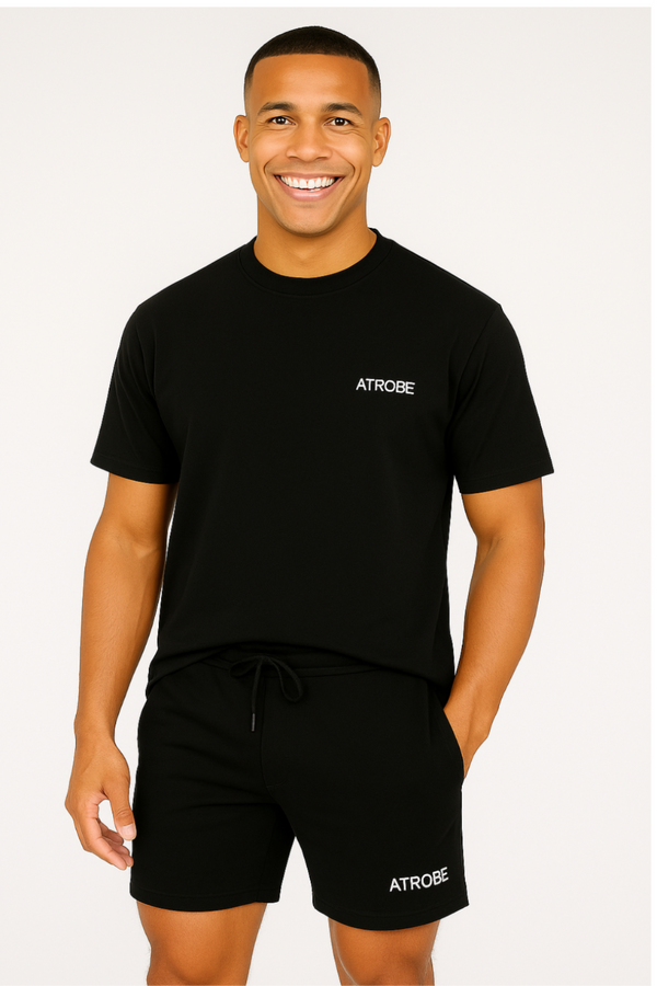 Man draagt zwarte Sakura Shadow set van Atrobe – bestaande uit T-shirt en korte broek met minimalistisch logo
