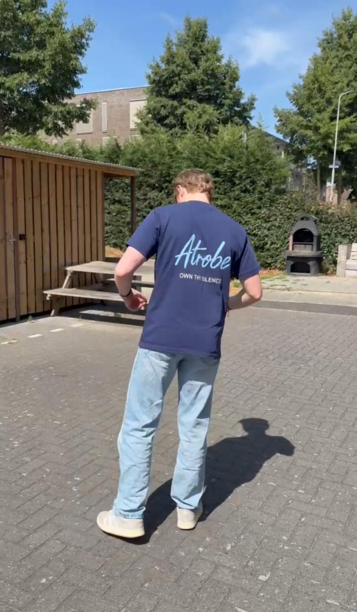 Model foto met het atrobe signature shirt in het blauw met ook own the silence achterop 